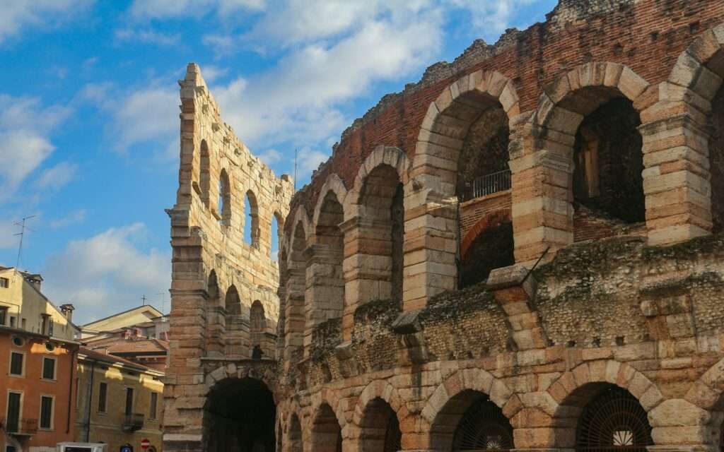 The Roman arches of the Arena di Verona under a blue sky